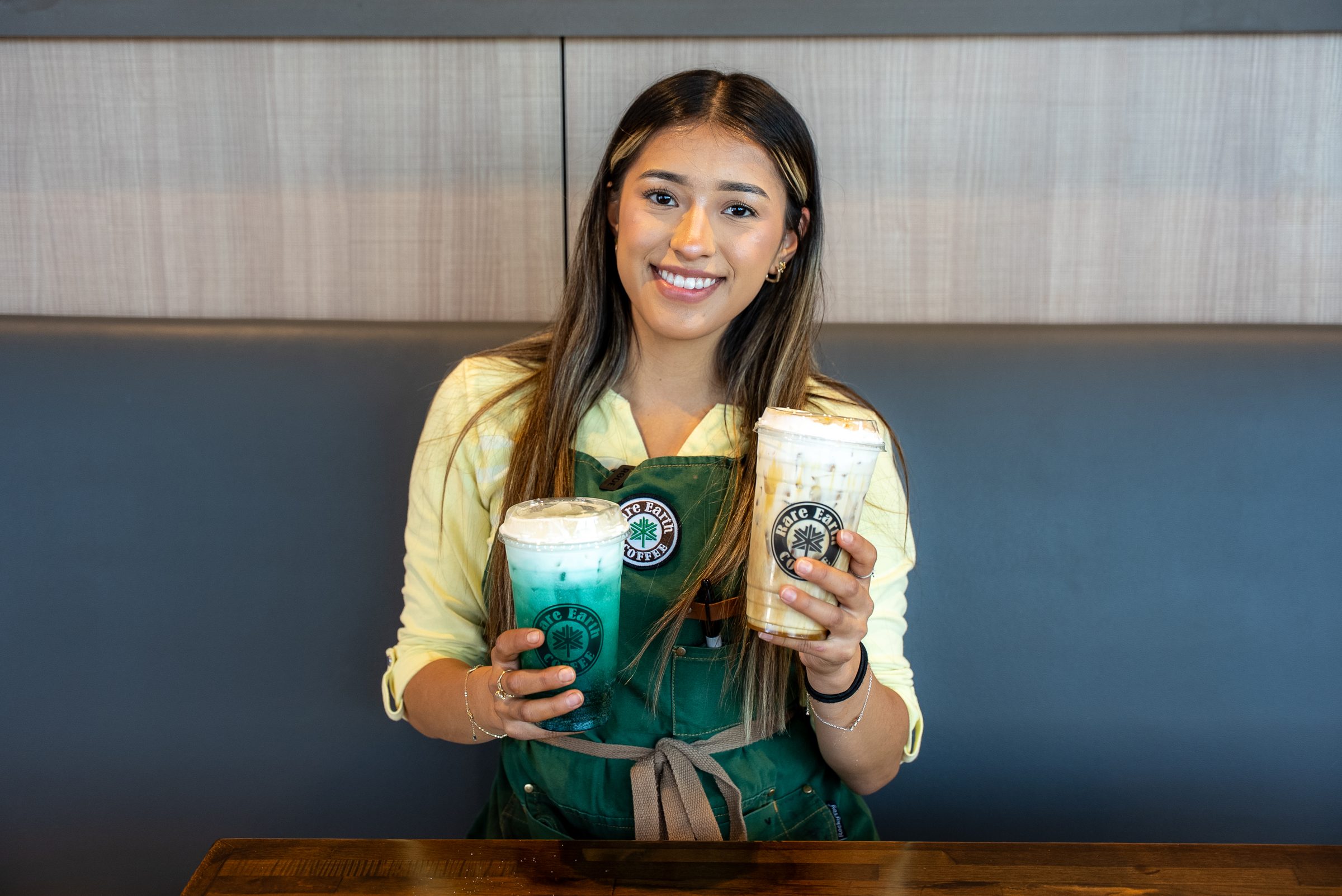 Barista with two drinks smiling
