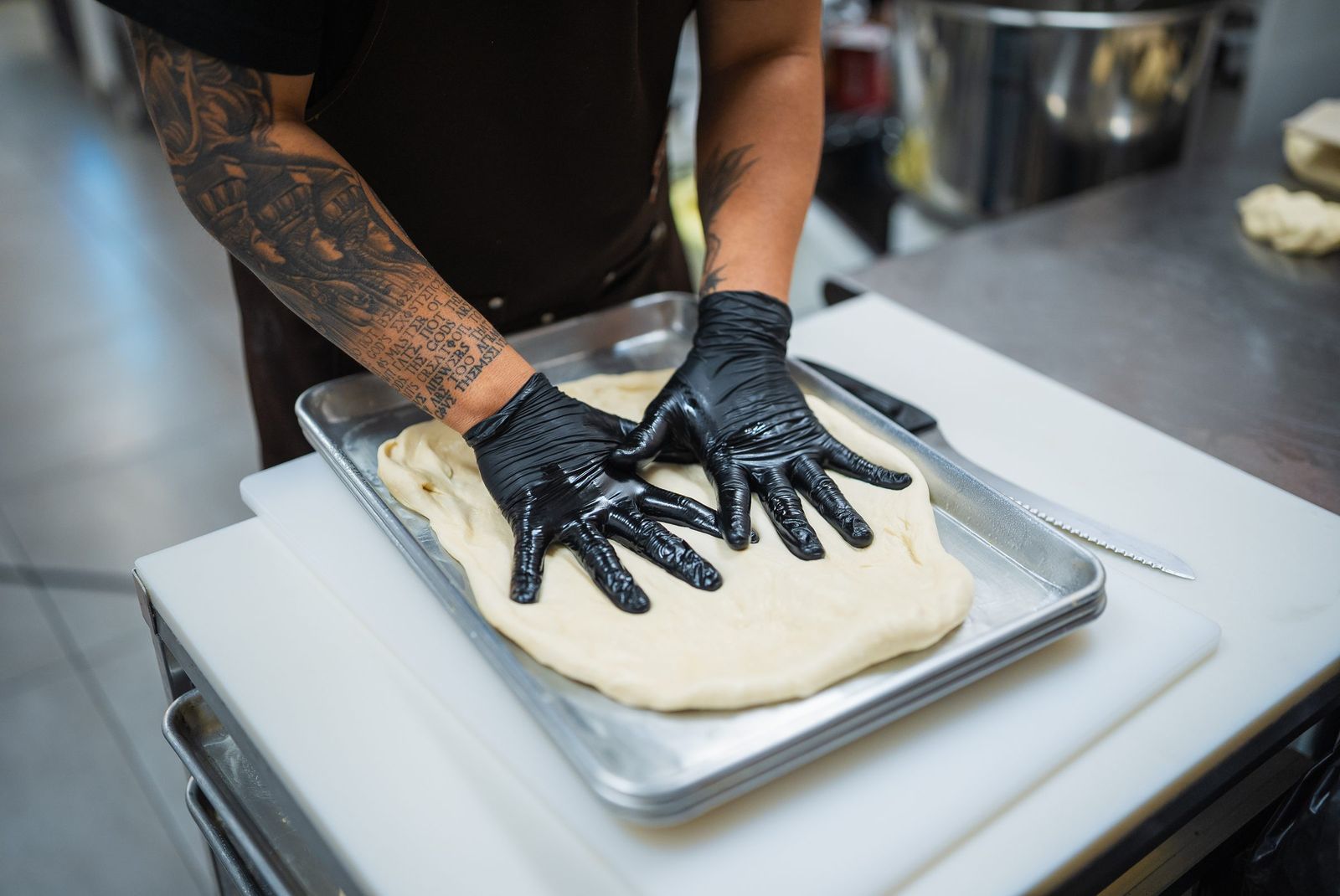 Gloved hands pressing dough into a pan